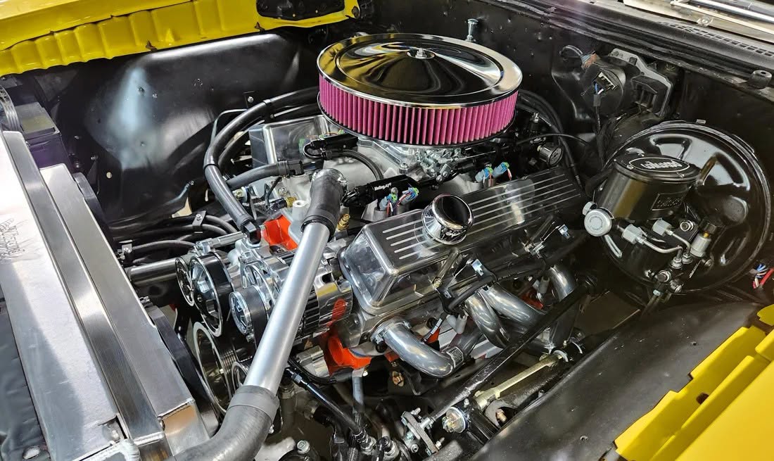 Polished headers clearing the steering and suspension on a small-block V8 in a classic car