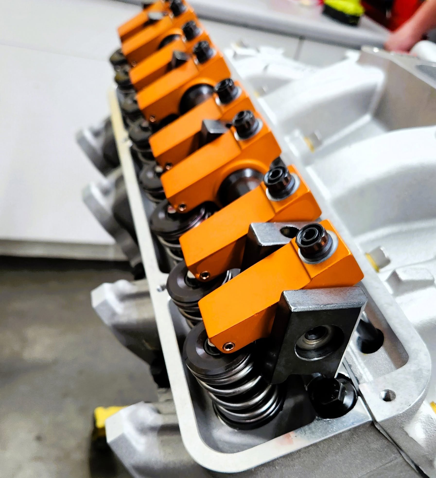 Orange shaft-mount rocker arms installed on an aluminum cylinder head